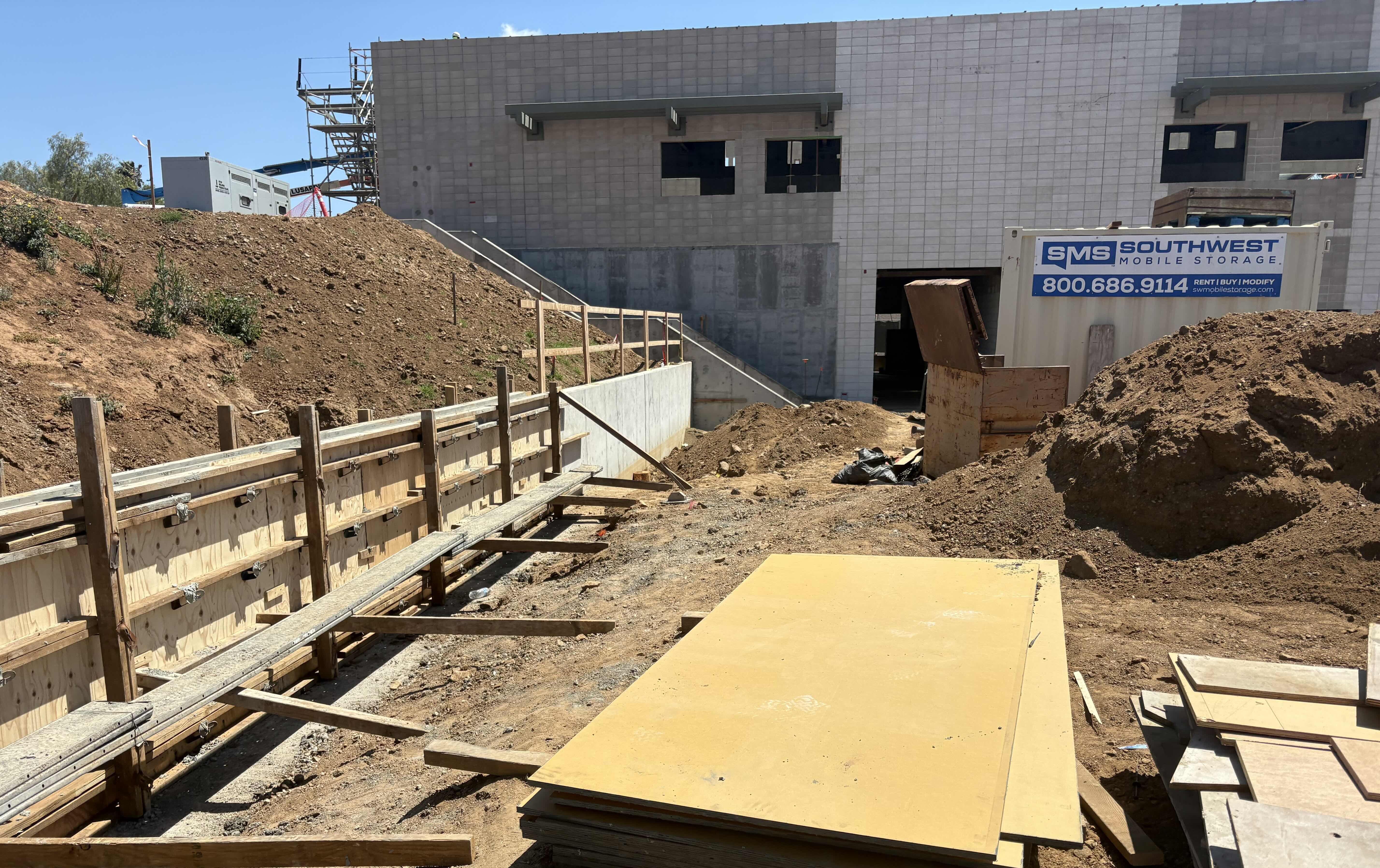 Construction site with a partially built building and wooden barriers.