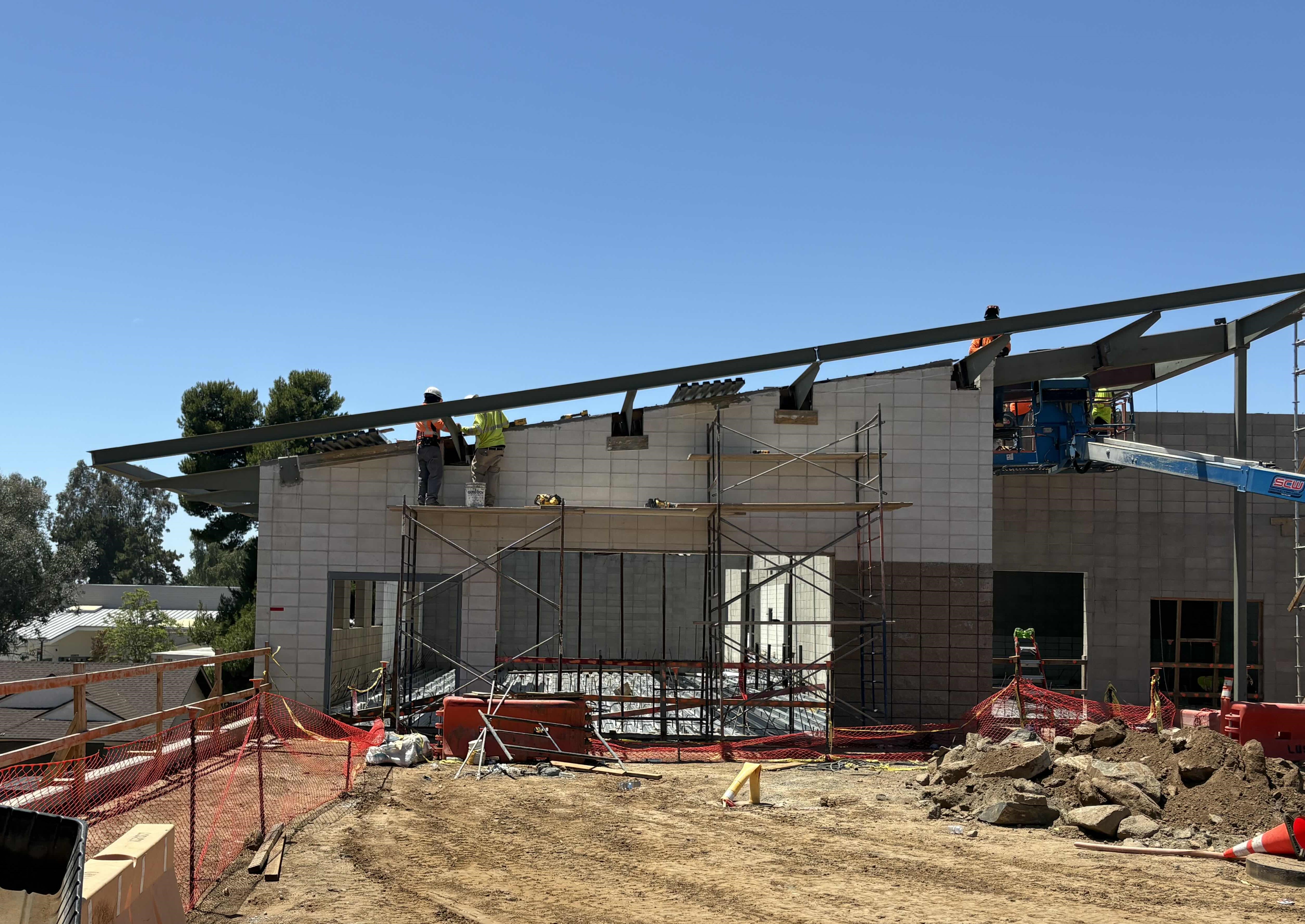 Construction workers are building a new structure on a sunny day.
