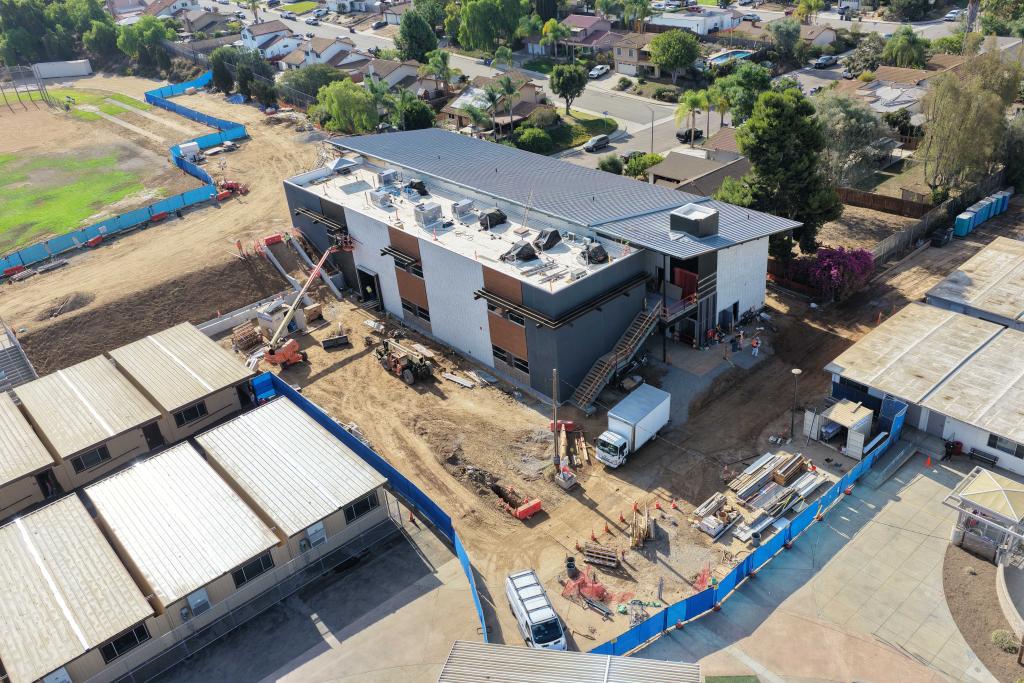Aerial view of a modern building under construction with scaffolding and cranes.