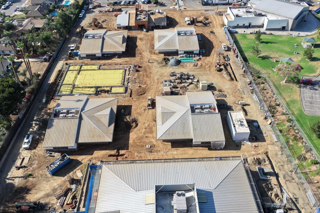 An aerial view of a large construction site showing multiple buildings in progress with metal roofs.