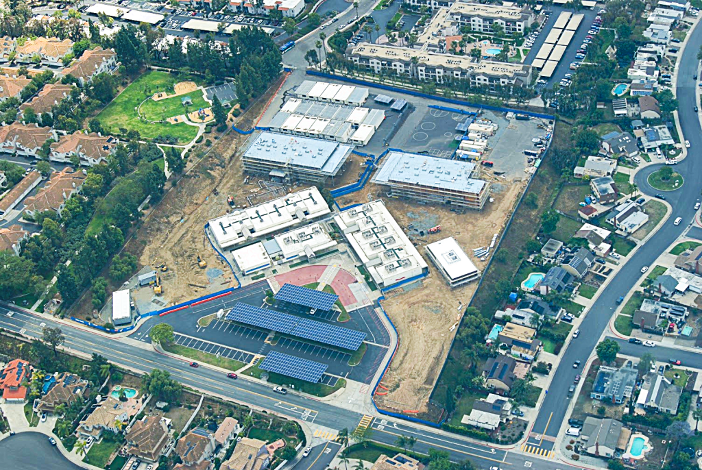 Aerial view of a construction site with multiple buildings and solar panels.