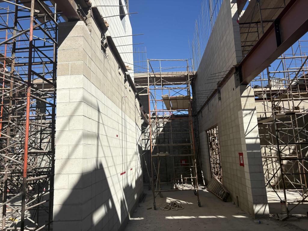 Construction site with scaffolding and concrete structures under a clear blue sky.