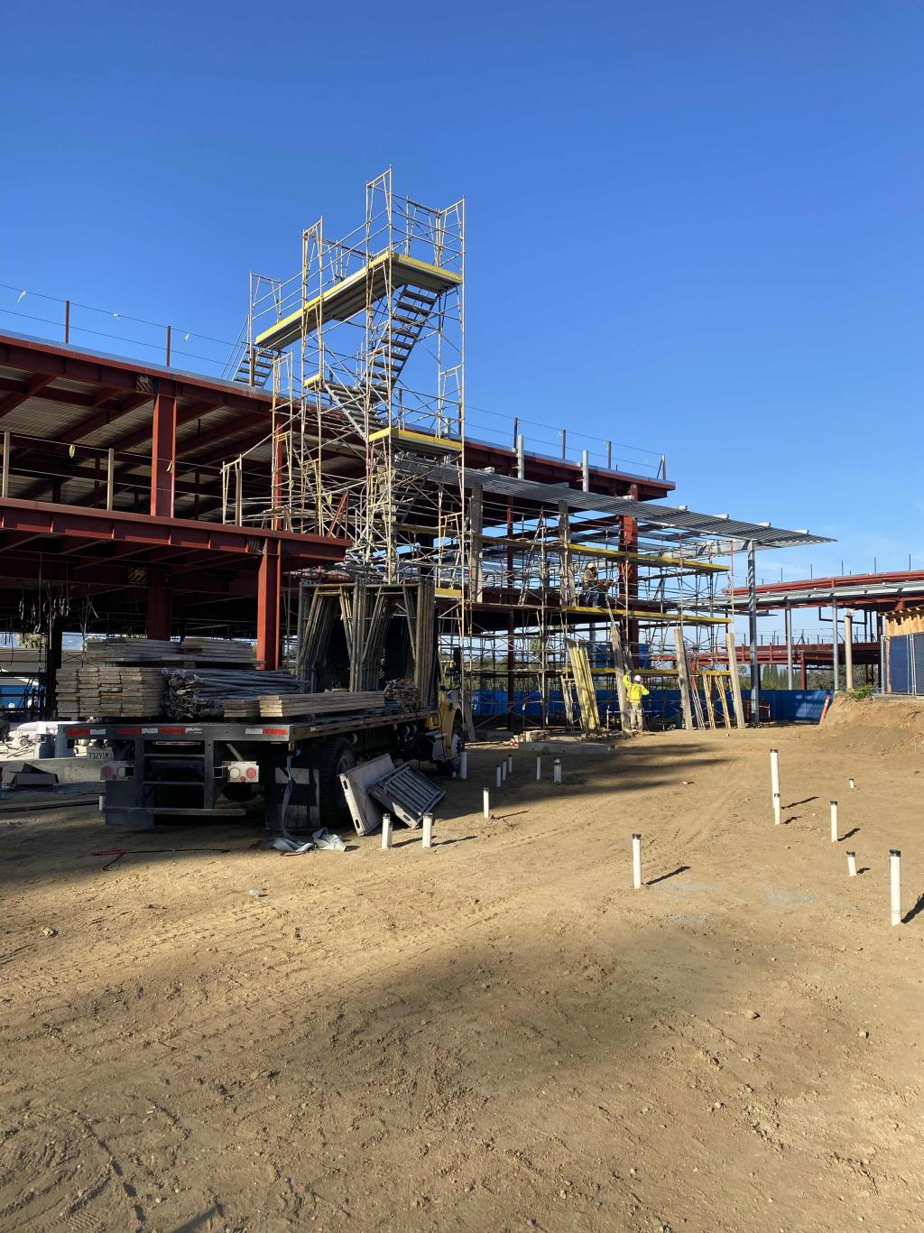 Construction site with scaffolding and steel framework under a clear blue sky.
