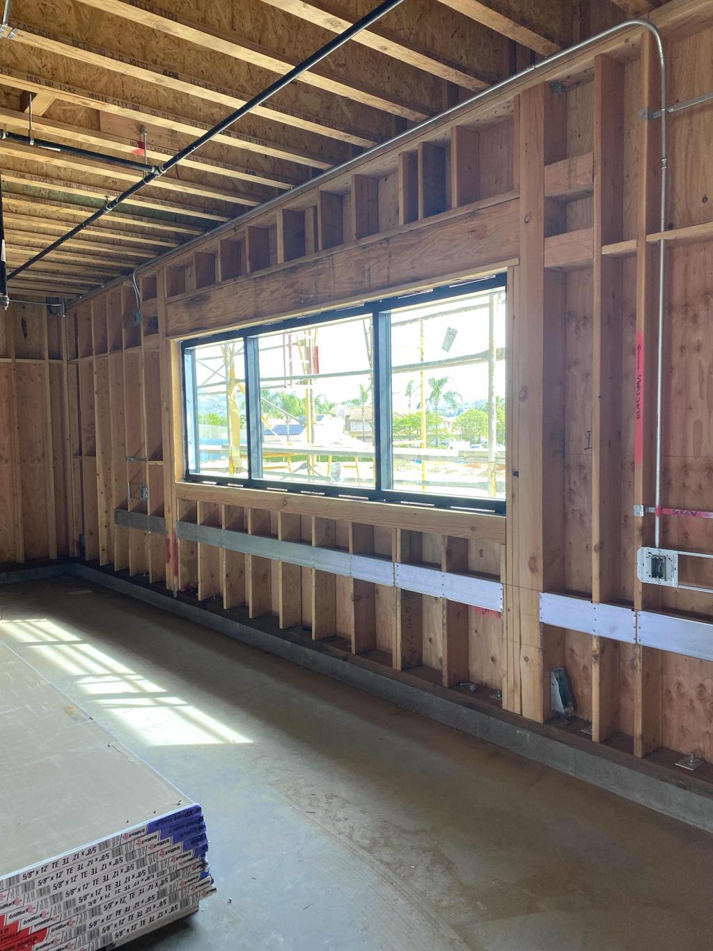 Interior view of a building under construction, showing wooden framing and a window.