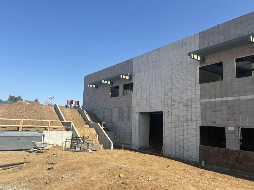 A modern building under construction with concrete walls and a clear blue sky.