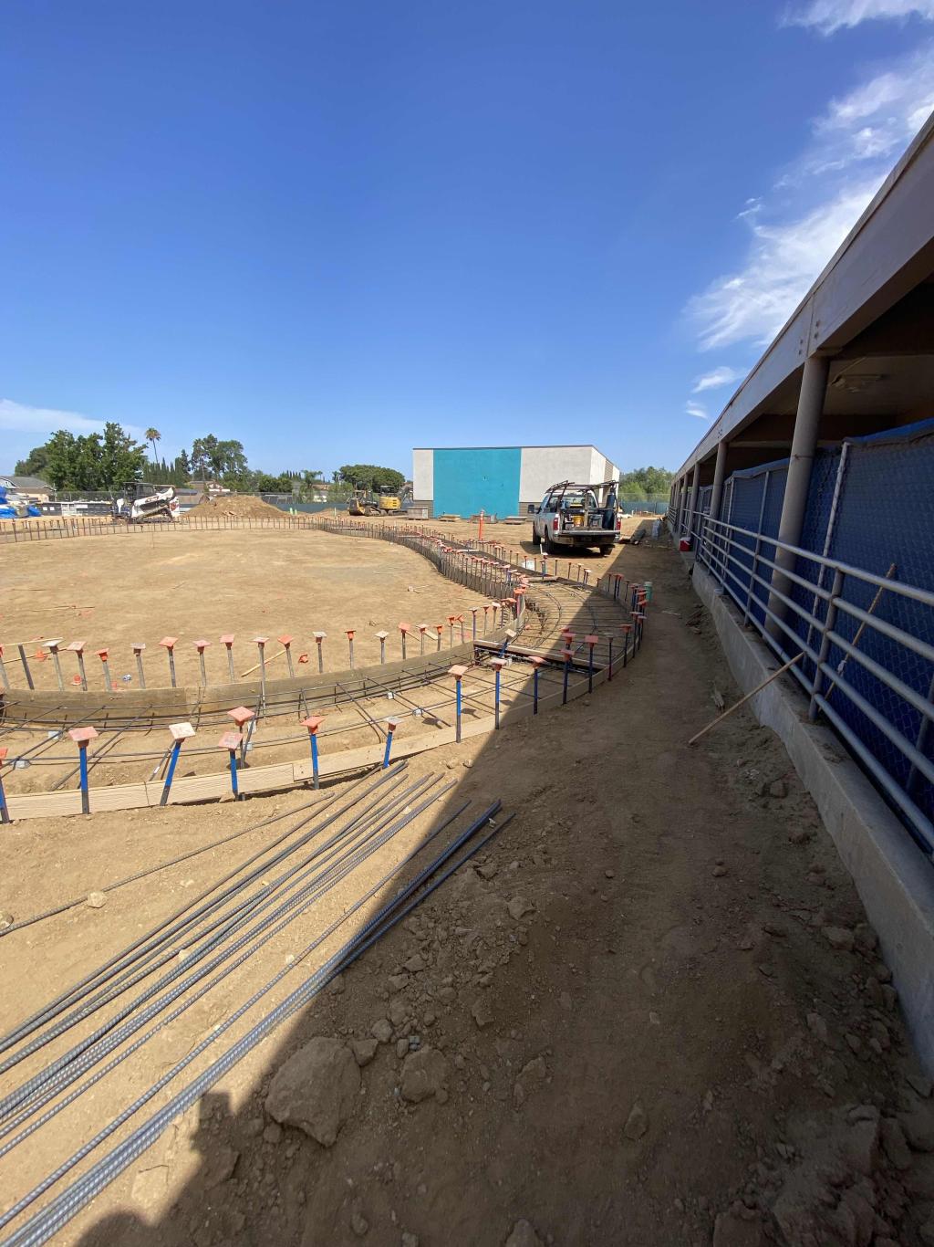 Construction site with a large circular foundation and metal rebar under a clear blue sky.