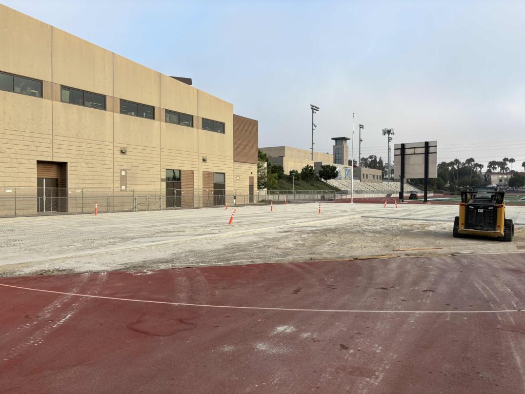 A wide-angle view of a large, beige building next to an open paved courtyard.