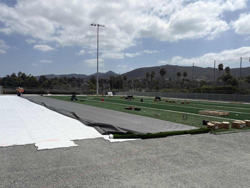 A wide-angle view of a large outdoor area with white sheets laid out on the ground under a partly cloudy sky.