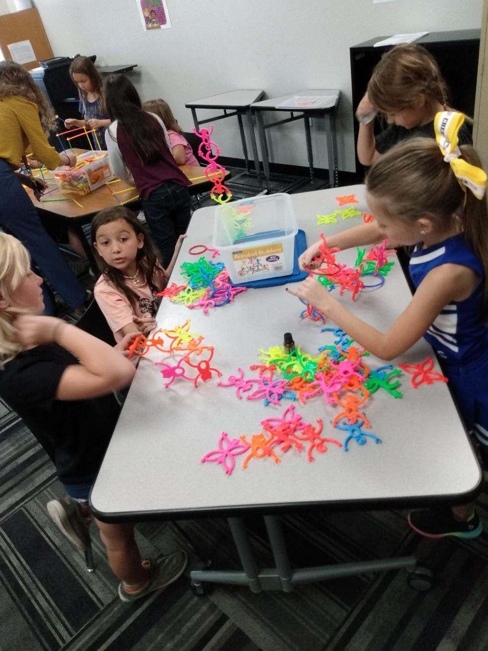 Children sitting at a desk playing with connect monkey toys together