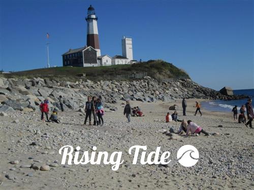 People enjoying the beach as the tide rises, with the words "rising tide" written in the sand.