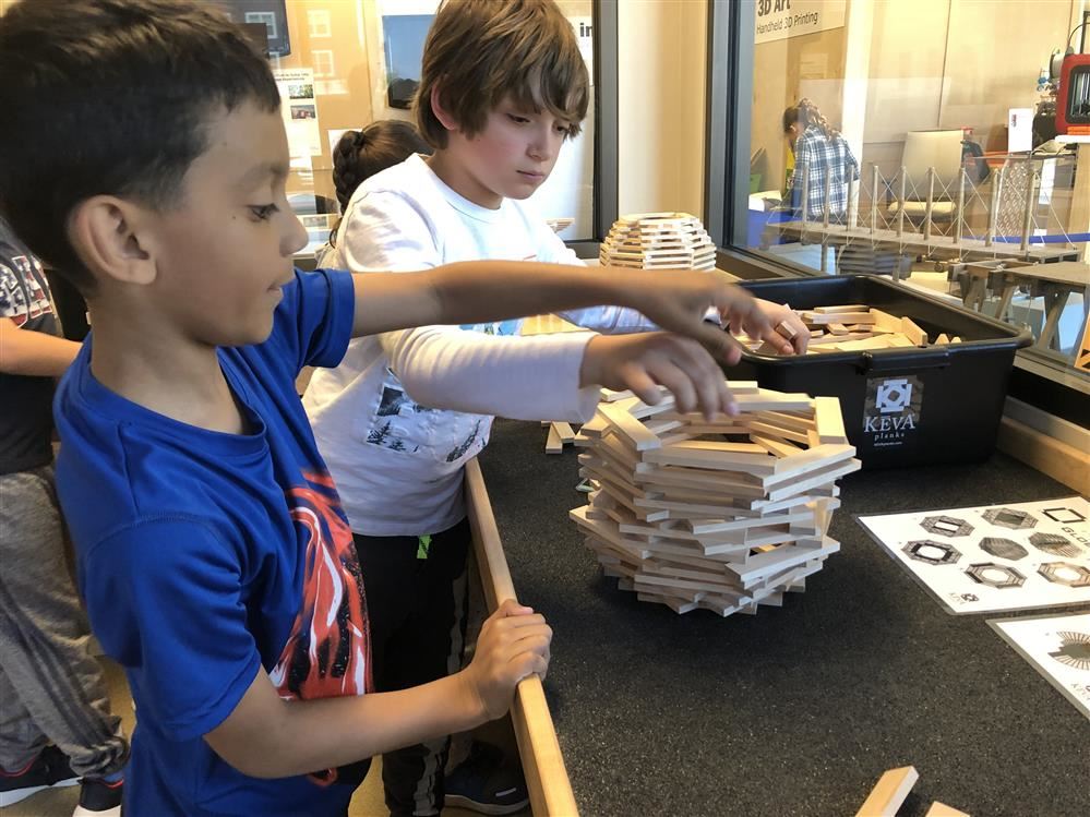 Two boys at Long Island Science Center building a tower with wooden blocks.