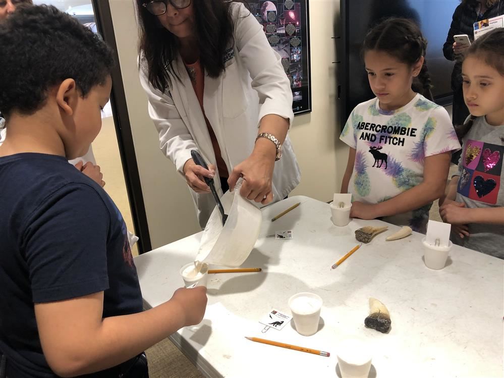 Woman guiding kids in a science project at the Long Island Science Center.