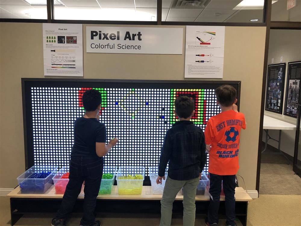 Two boys playing with a pixelated display at the Long Island Science Center.
