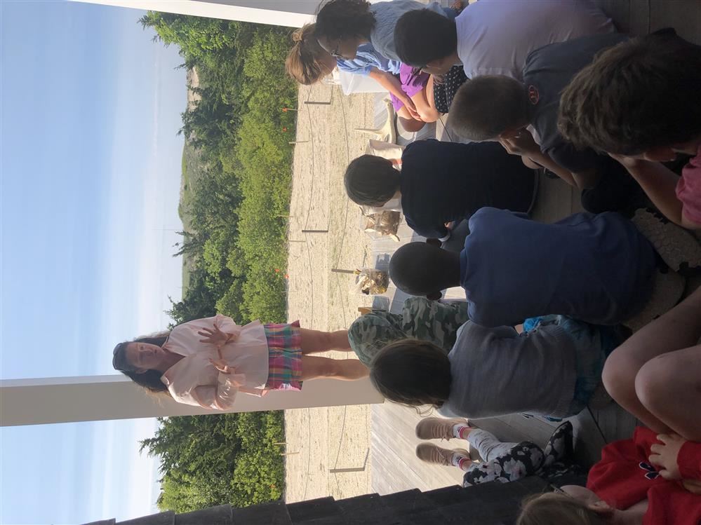 A woman giving a talk to children at Dinosaur Dig/Lifesaving Station.
