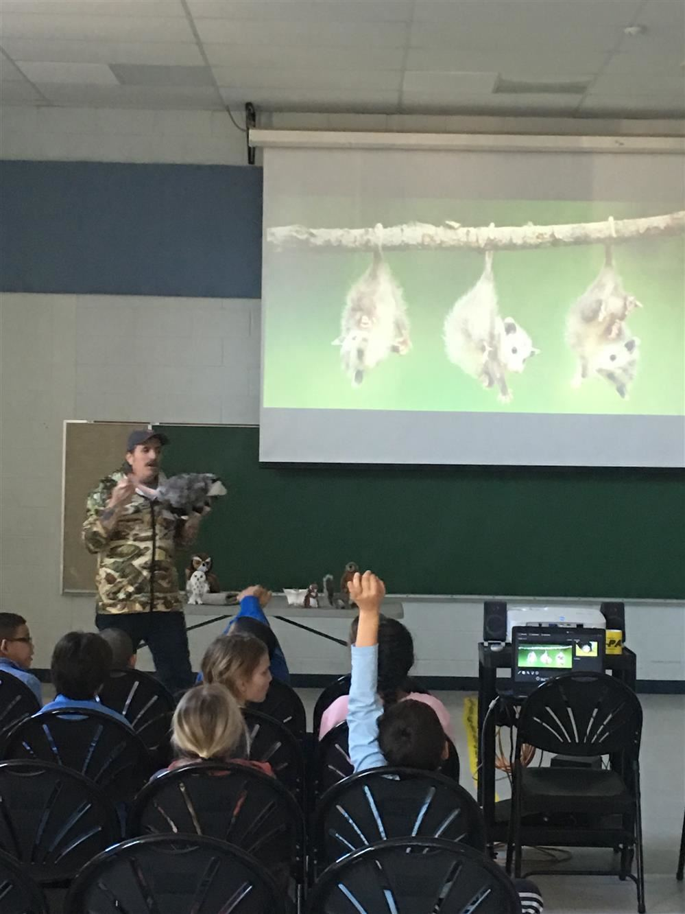 A man in camouflage giving a presentation to children