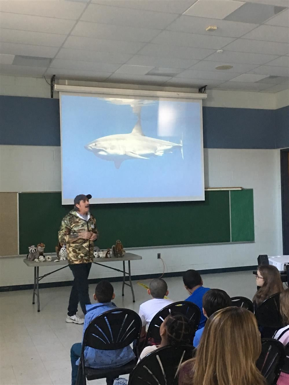 A man giving a presentation to kids in a school classroom.