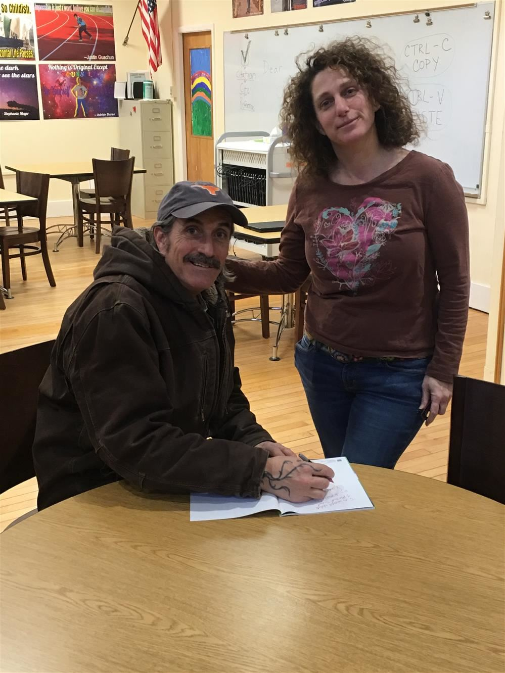 A man and woman signing papers at a table