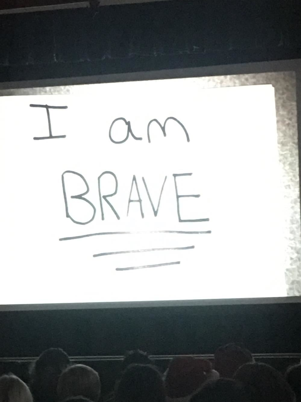 People watching the screen displaying the words "I am brave."
