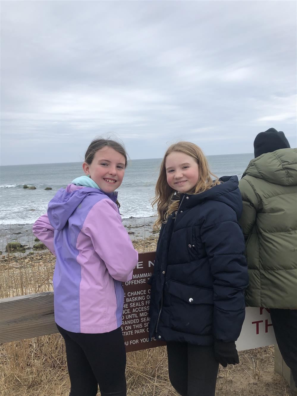 Two young women posing by the beach