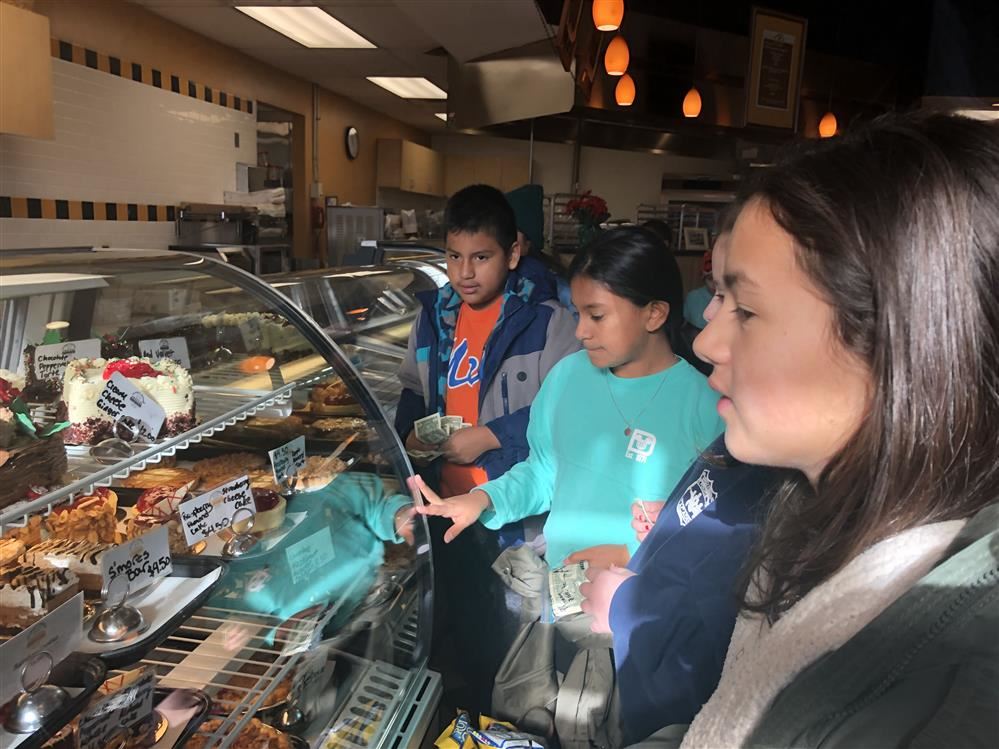 A diverse group of individuals observing a delightful assortment of pastries on a display counter.