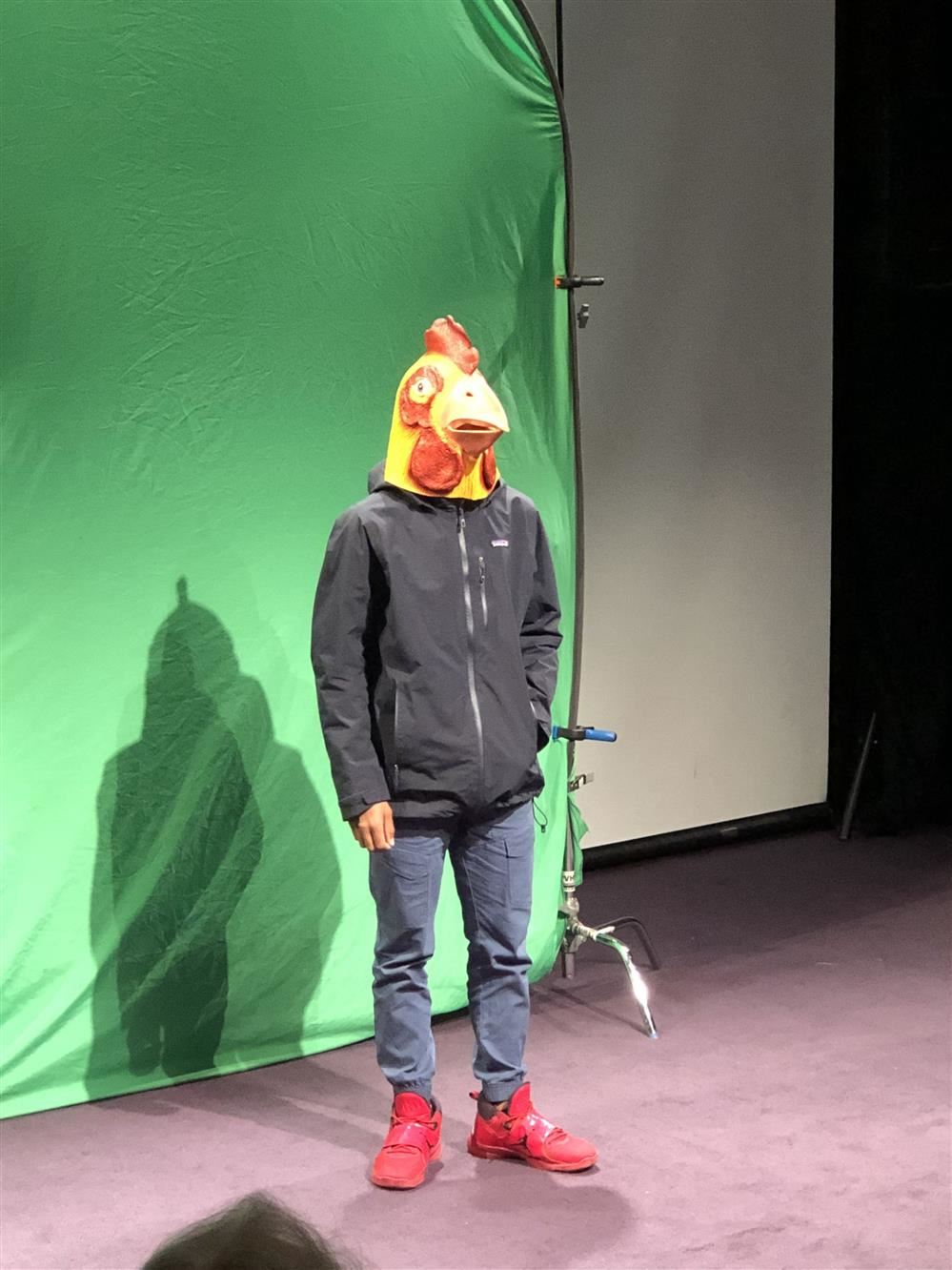  A man in a chicken mask performing on stage.