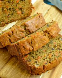 Sliced loaf of carrot bread on a wooden cutting board.