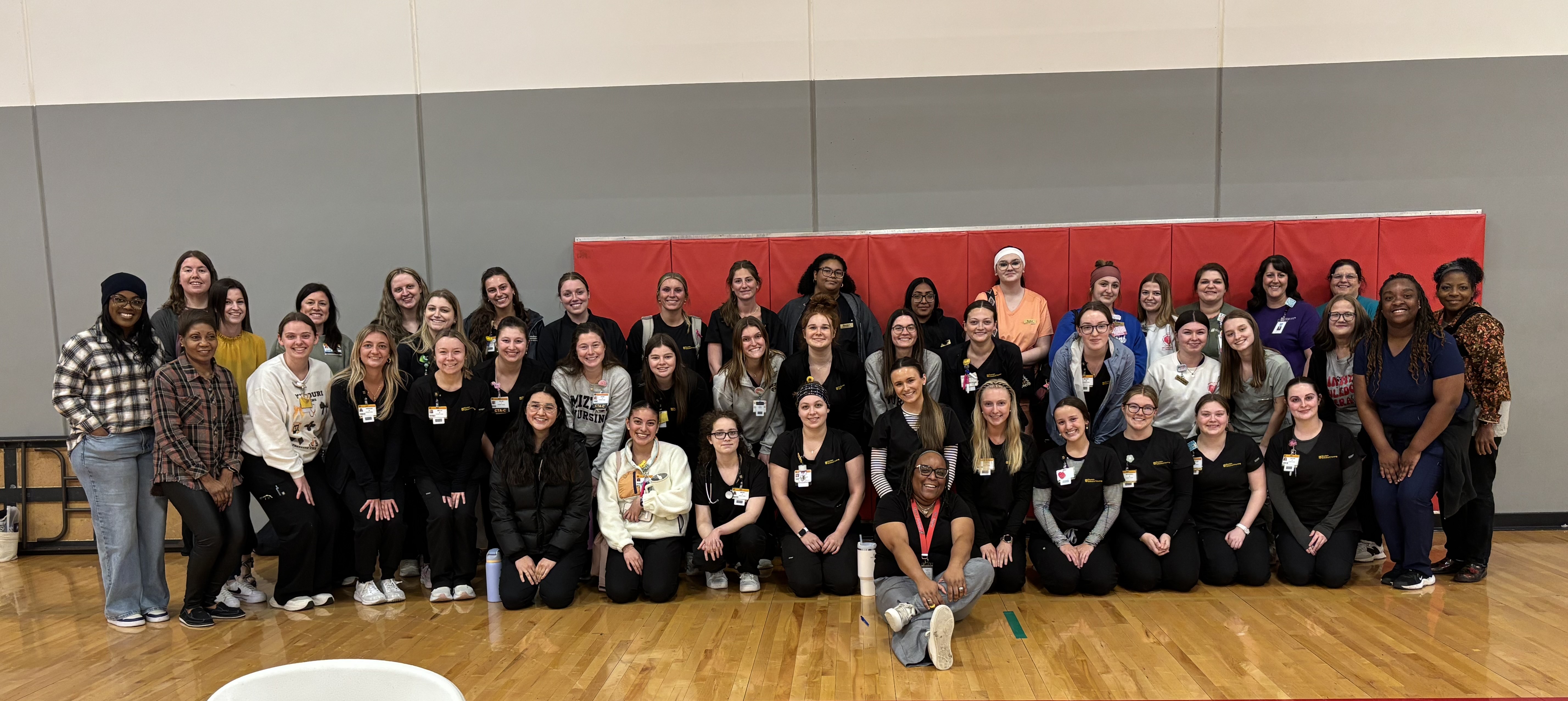 A large group of volunteers posing for a photo in the middle school gym