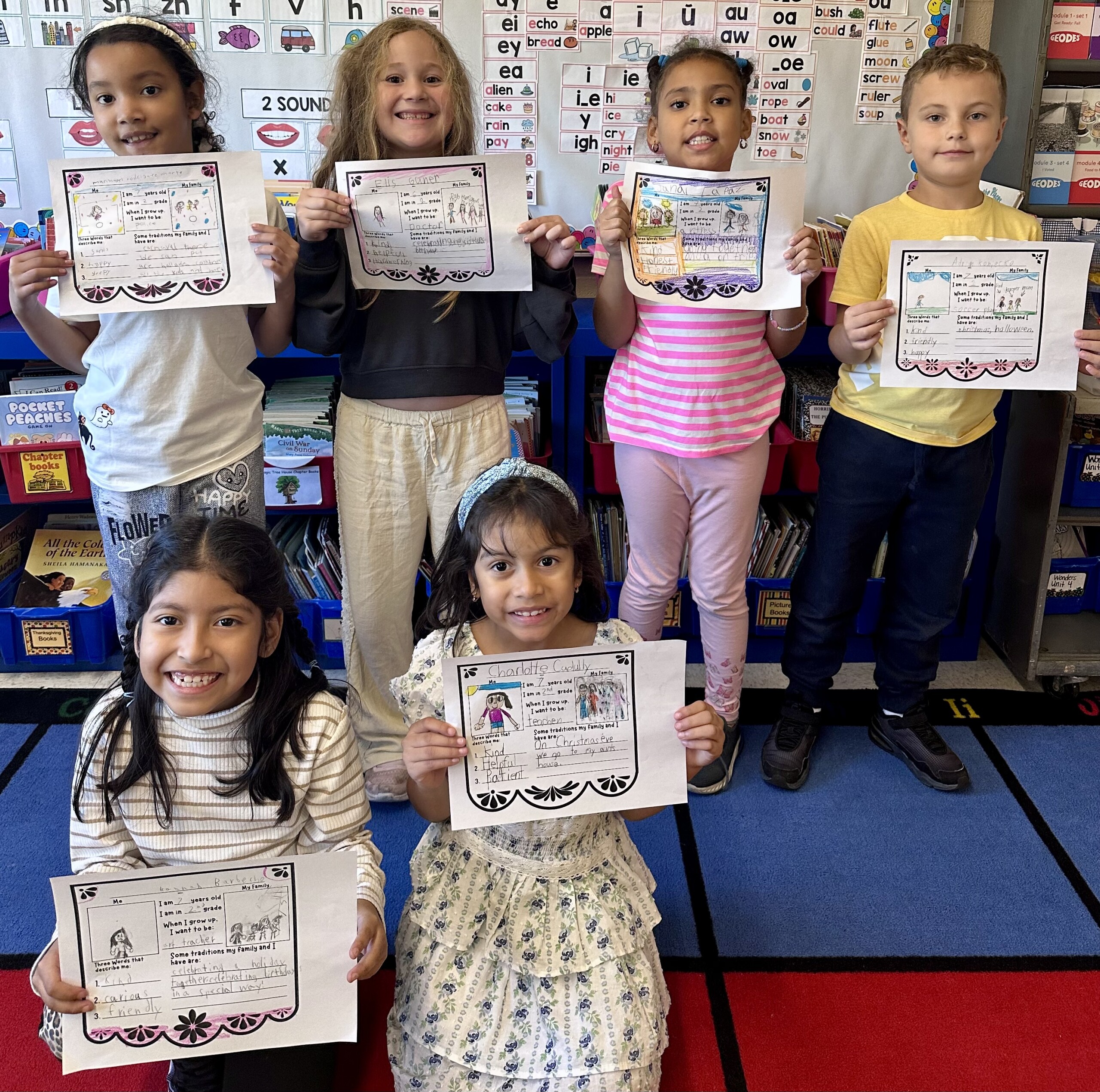 Six smiling children proudly hold up their achievement certificates in a brightly decorated classroom.