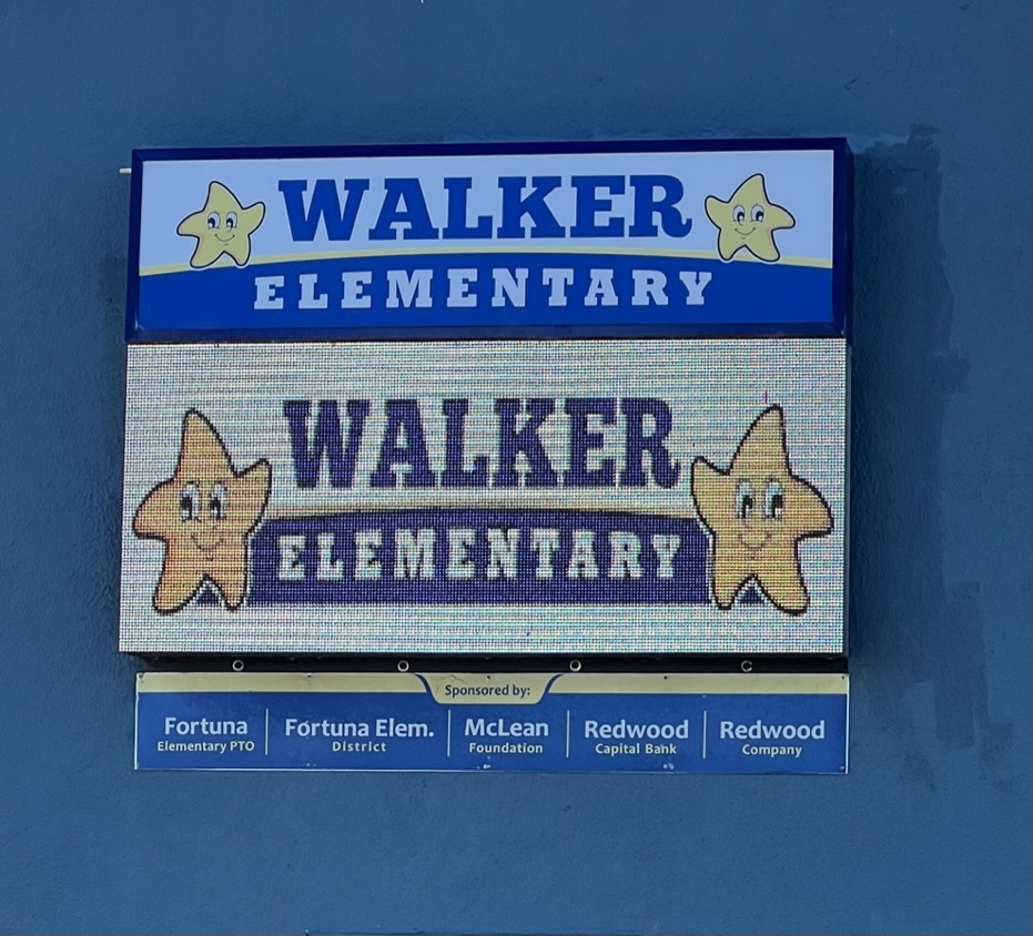 Two signs for Walker Elementary School, one with blue and yellow stars, the other with cartoon stars.