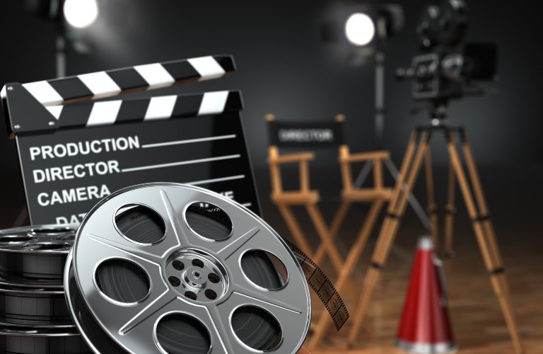A film set with a clapperboard, film reel, vintage camera, and director's chairs.