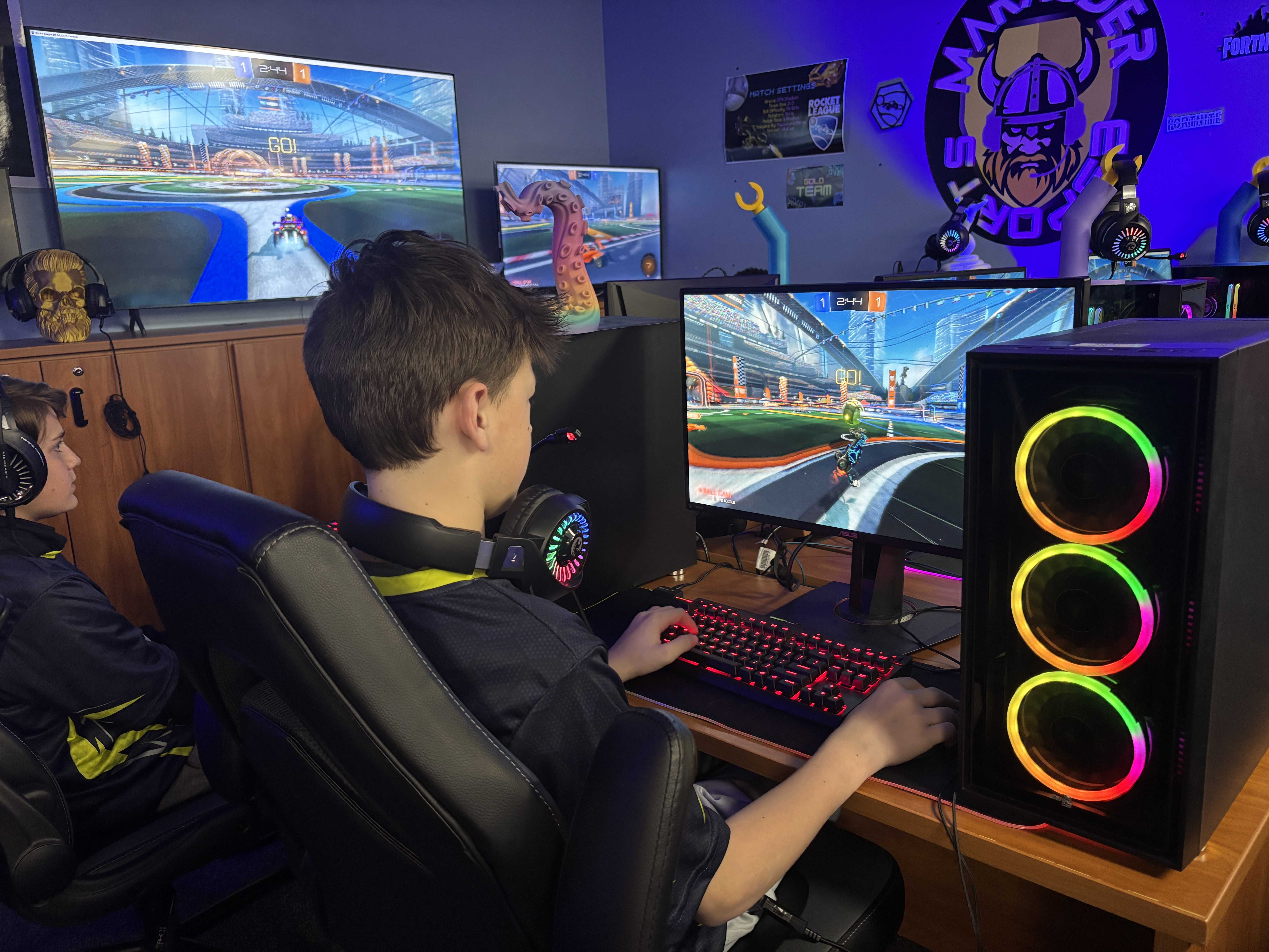 Two people are gaming, focused on their computer screens.