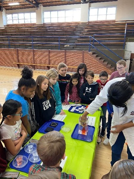 A group of students are gathered around a table with a science experiment.