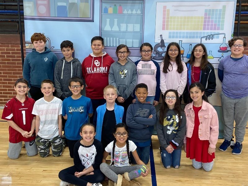 A group of students posing for a photo in front of a colorful backdrop.