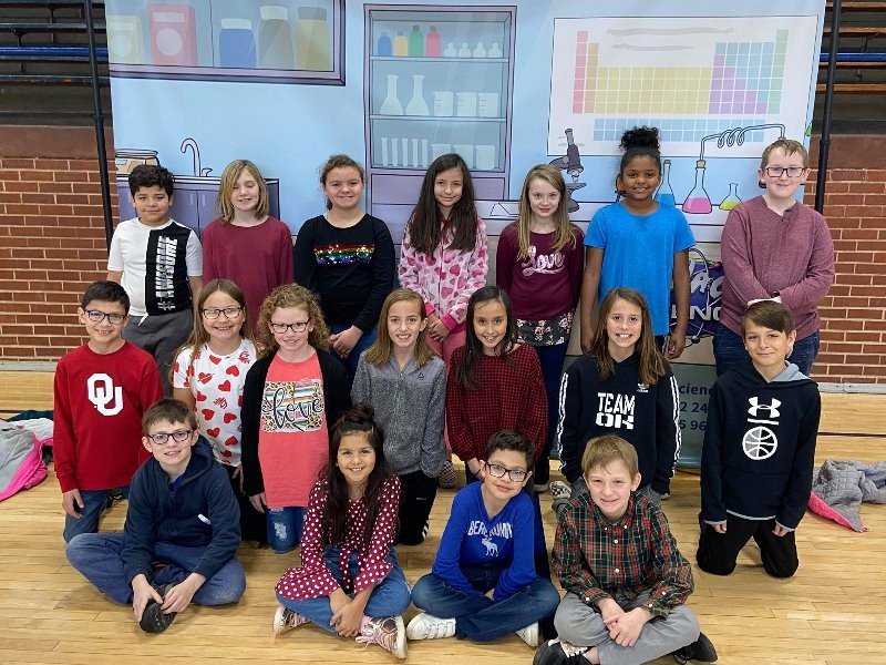 A group of students posing for a photo in front of a science-themed backdrop.