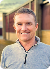 A man with short brown hair smiles warmly at the camera.