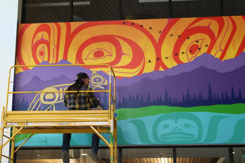 The artist Teak adds finishing touches to his Native American mural in the new Cascade Middle School.