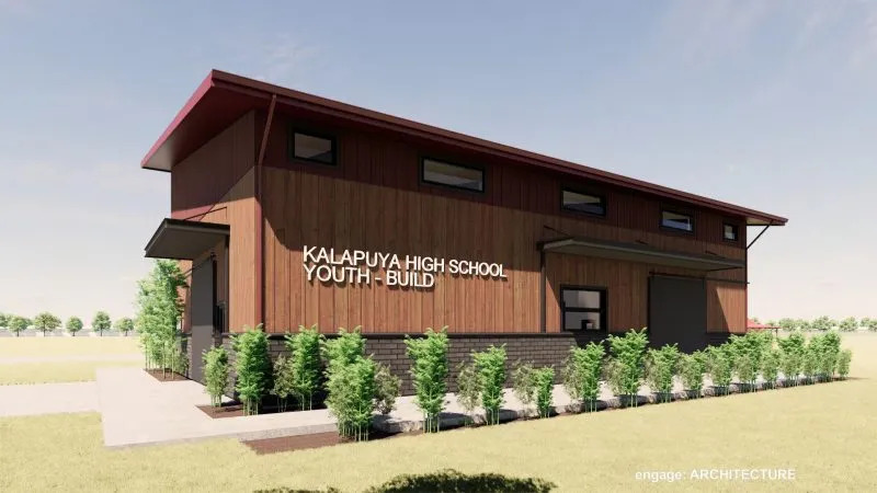 An exterior view of the Kalapuya High School Youth-Build building, featuring a wooden facade and a red roof.