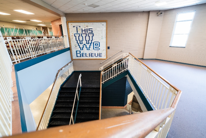 A wide shot of a modern library staircase with a large "The 100 Who Built Delaware" sign.