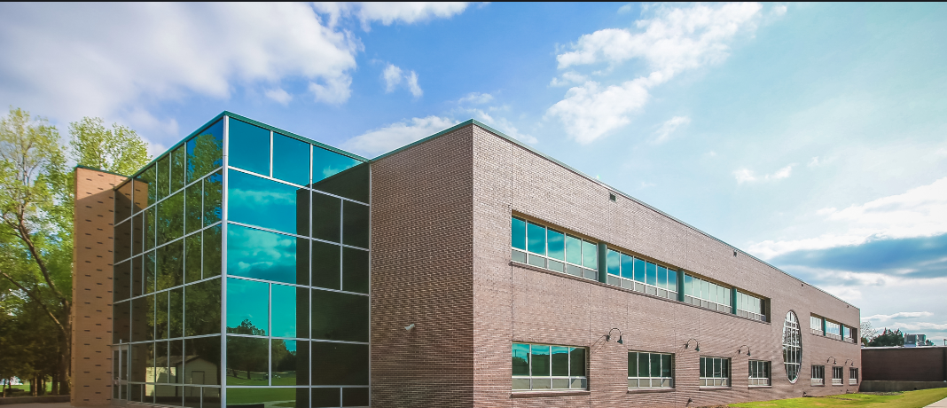 Modern building with glass and brick exterior under a blue sky.