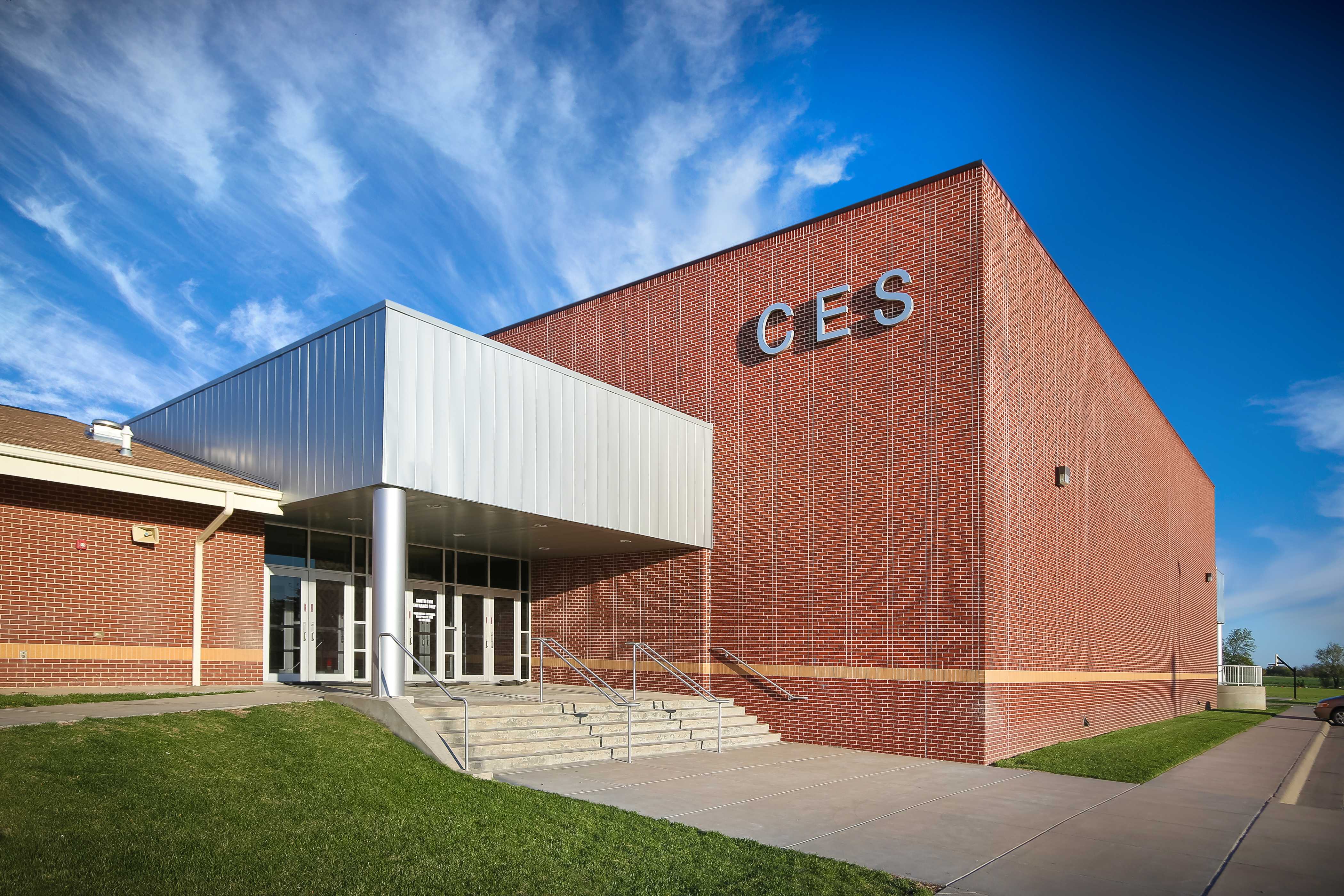 A modern brick building with the letters 'GES' on the side under a bright blue sky.