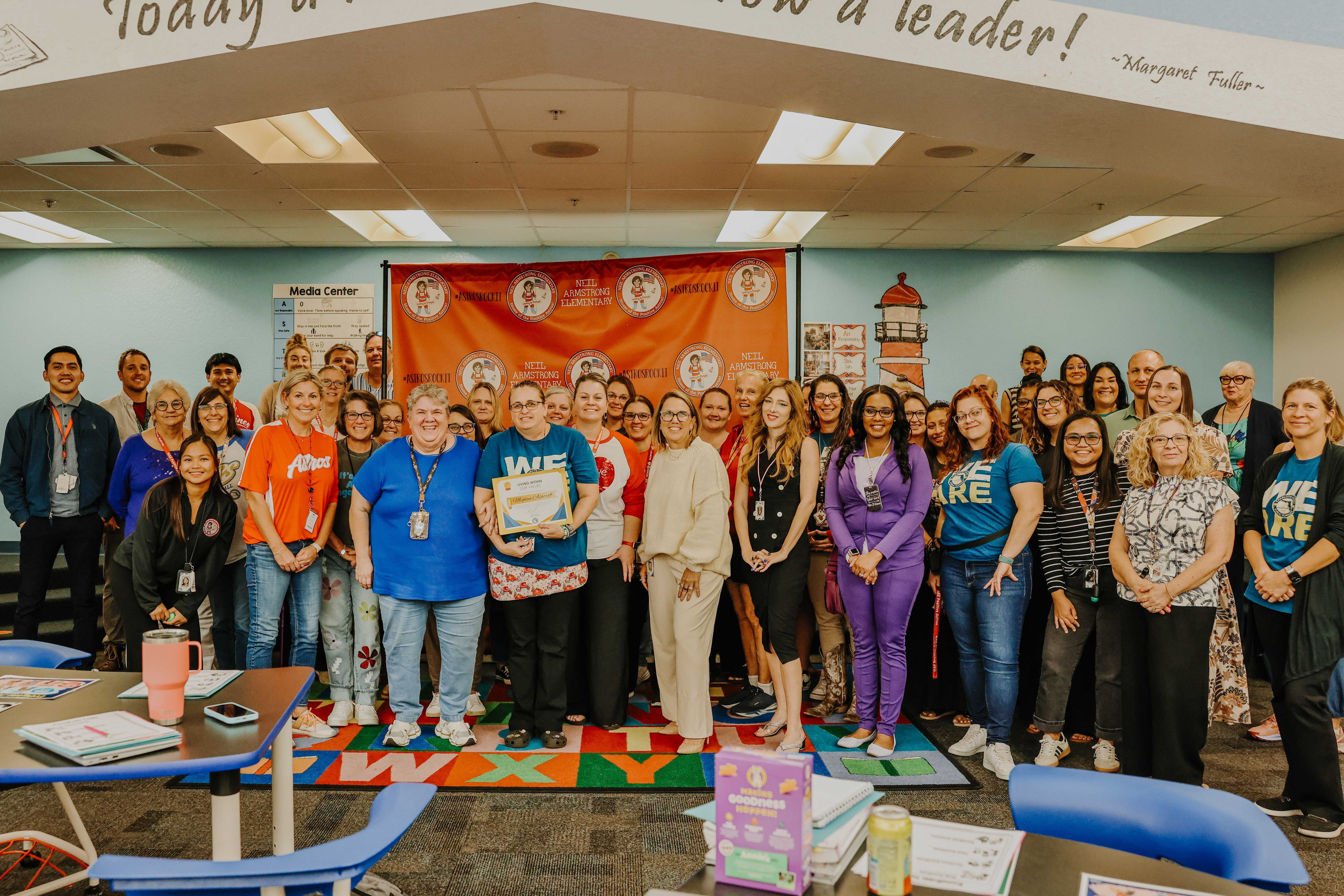 A large group of people pose together indoors, smiling at the camera.