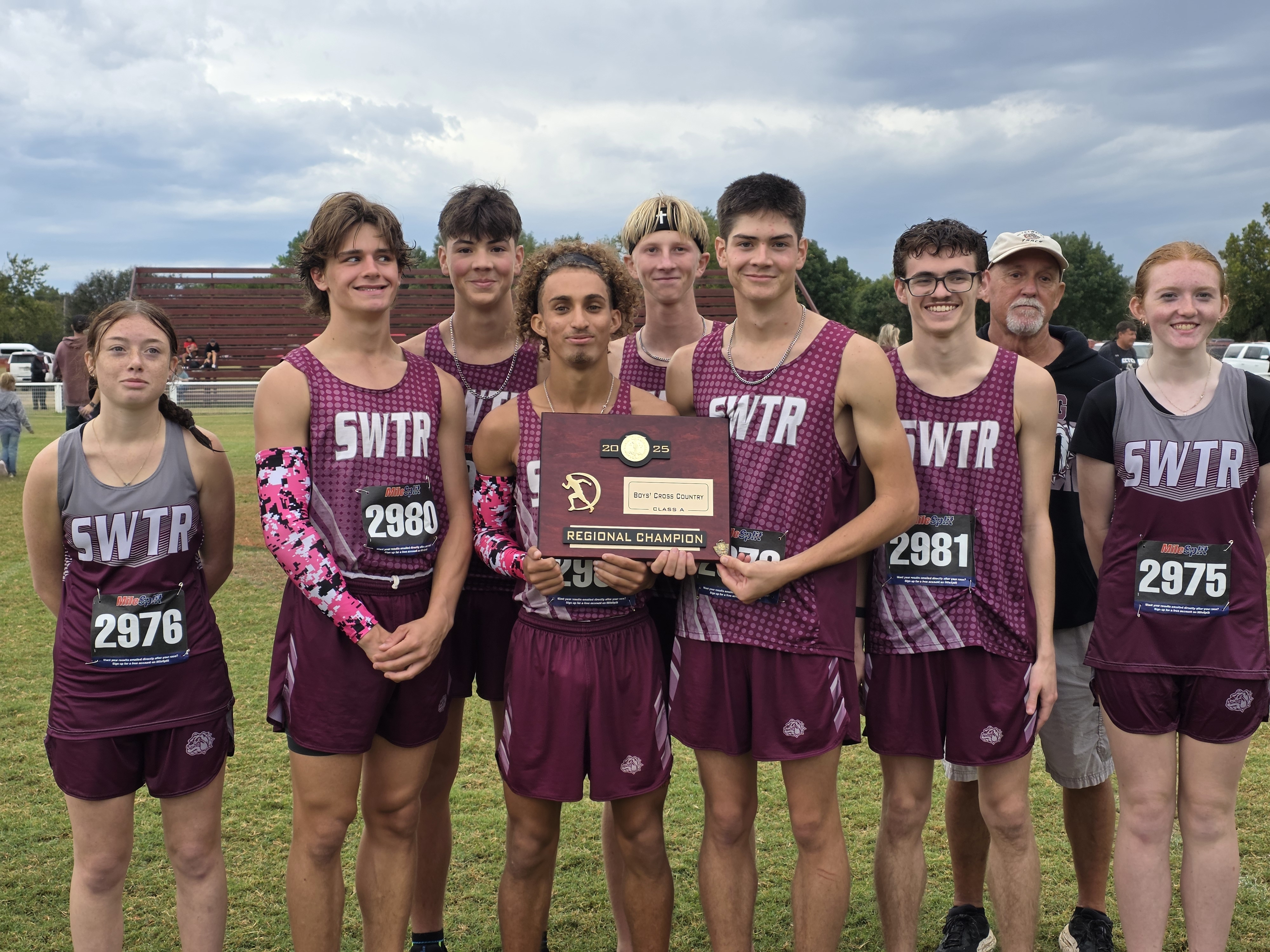 A cross-country team poses with a trophy, wearing matching maroon and white uniforms.