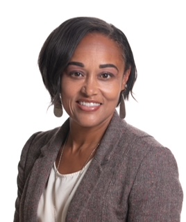 A woman with short black hair smiles at the camera, wearing a gray blazer and white shirt.