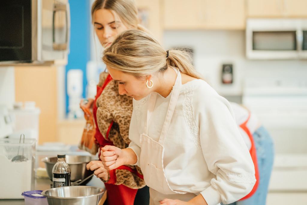 WHS students in a kitchen, focused on a mixing bowl.