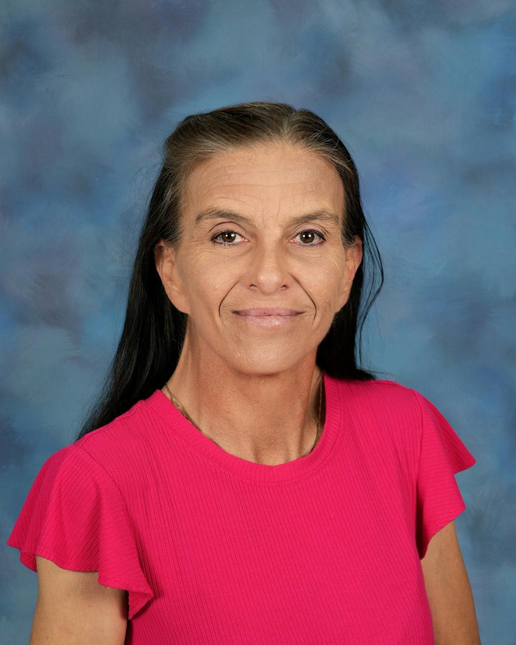 A woman with long dark hair smiles at the camera.