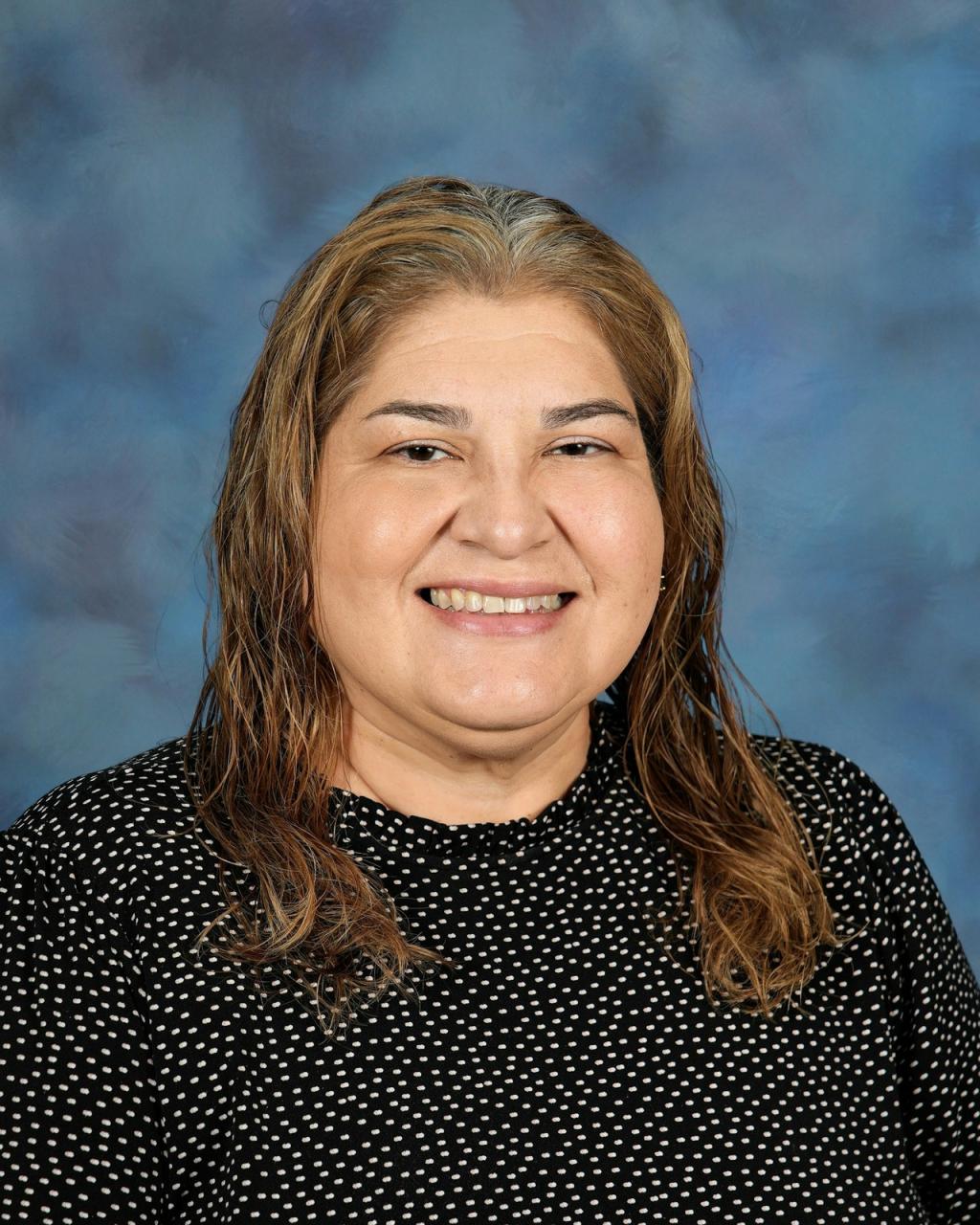 A woman with long brown hair smiles at the camera, posing for a portrait.