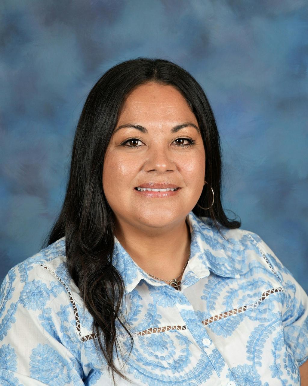 A woman with long dark hair smiles at the camera.