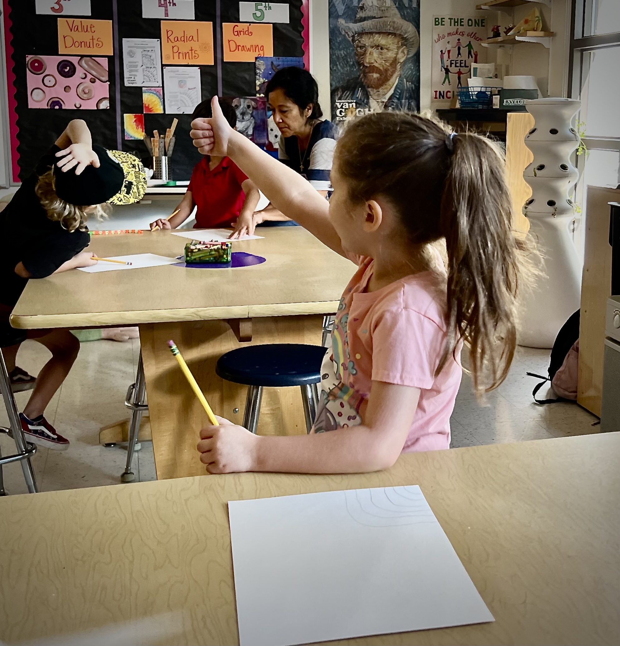 STudent in a classroom with a thumbs up