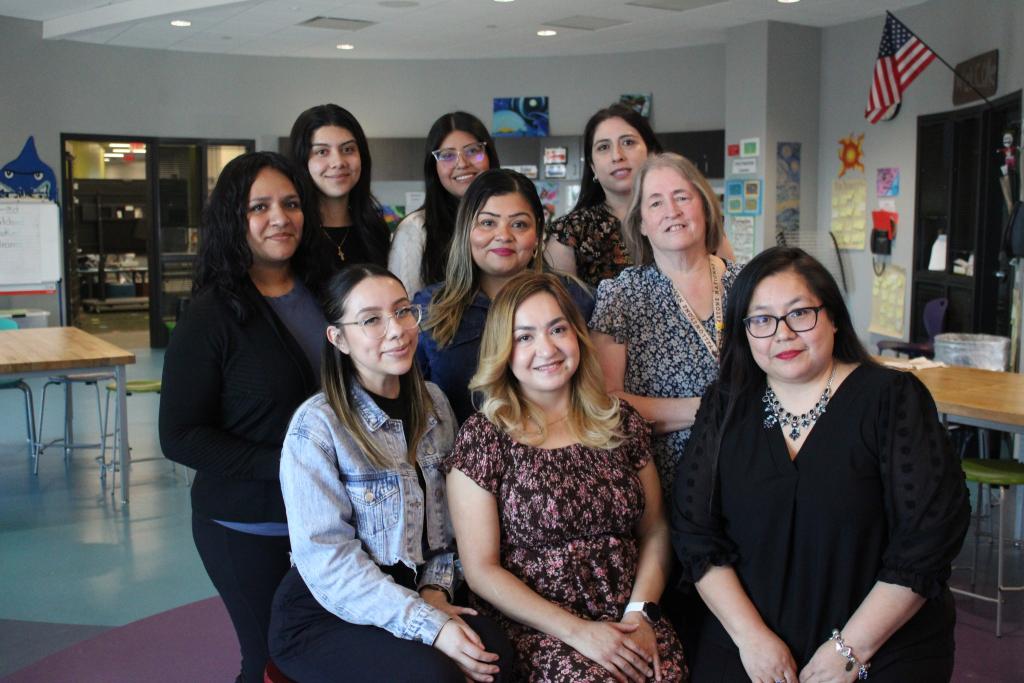 A group of women pose together, smiling for a photo.