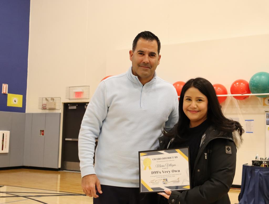 A man and a young woman pose for a photo, holding an award.